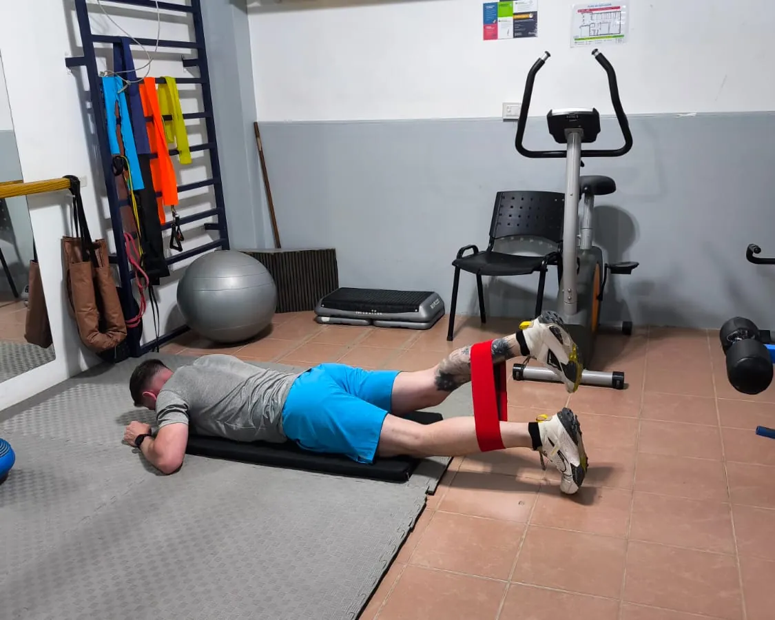 Paciente haciendo ejercicios con una banda elástica en el gimnasio del centro.