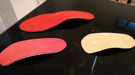 Tres plantillas Moplex terminadas sobre una mesa: dos rojas y una color crema.